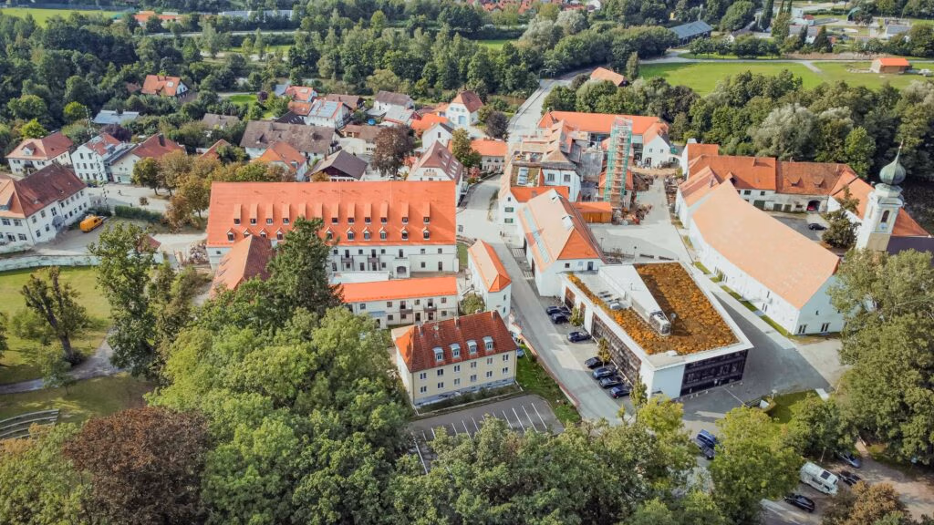 Eine kleine Ortschaft mit vielen Häusern umgeben von Natur und vielen Bäumen.